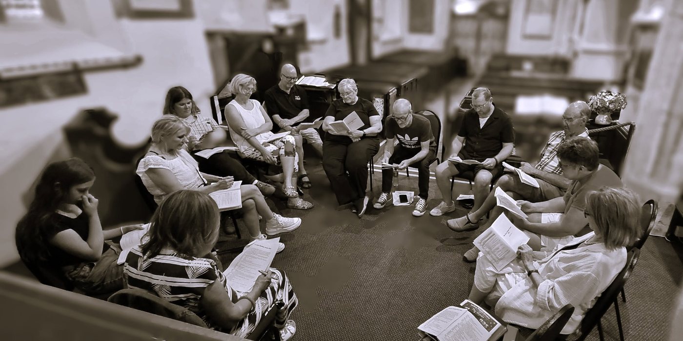 The Detling Players cast sitting in a circle reading scripts at a rehearsal for The Great Christmas Cracker Heist